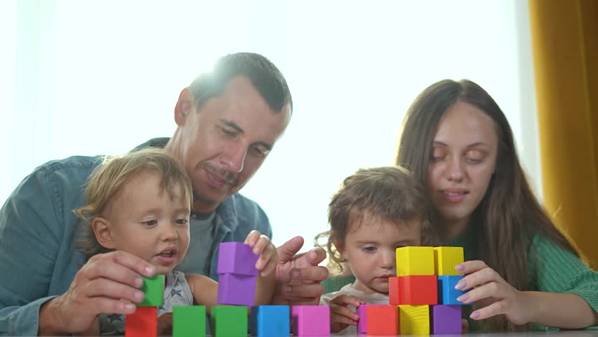 Family play with constructor home. Brother sister building blocks together. Parents guiding Brother sister constructor. Siblings learning play home. Family bonding time using constructor indoors.