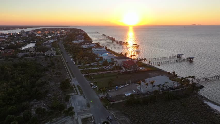 Aerial establishing shot of Apollo Beach in Tampa with luxury homes and houses along bay. Golden sunset time at horizon. Wide shot.