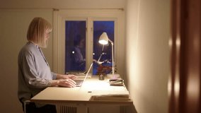 Female entrepreneur use standing desk to work online on laptop at night - Powered by Shutterstock - Get 15% off with code: PIKWIZARD15