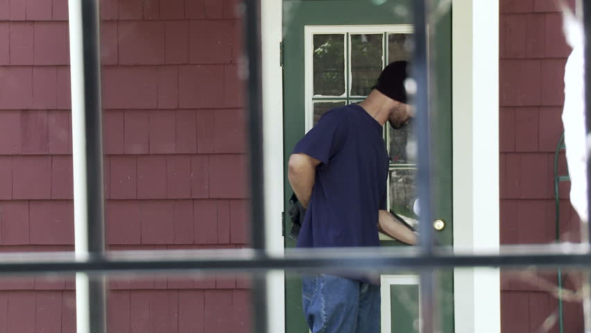 Burglar makes his way up to a house door, finds it locked and tries to open it