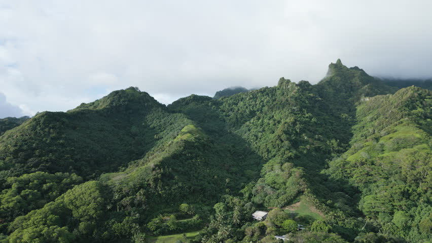 Drone establishing aerial pan right of cloud covered mountains in Rarotonga Cook Islands at sunrise