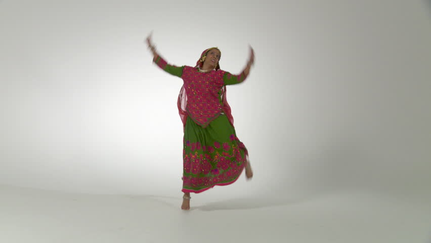 Indian girl in traditional folk dance costume spins as she dances against a