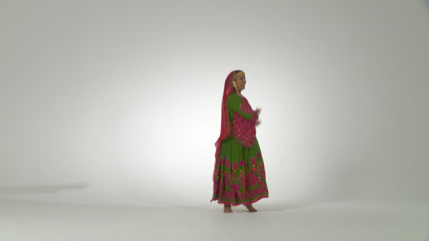 Indian girl in traditional folk dance costume dances energetically against a