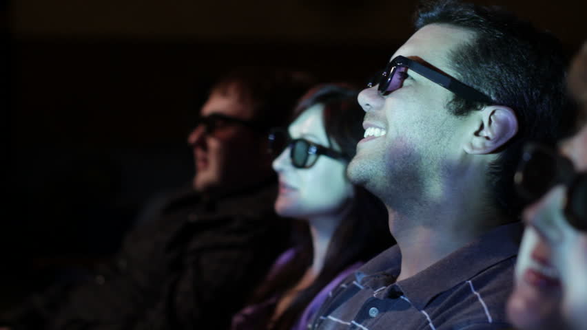 Young man watching a 3D movie with a group of friends, exchanging comments.