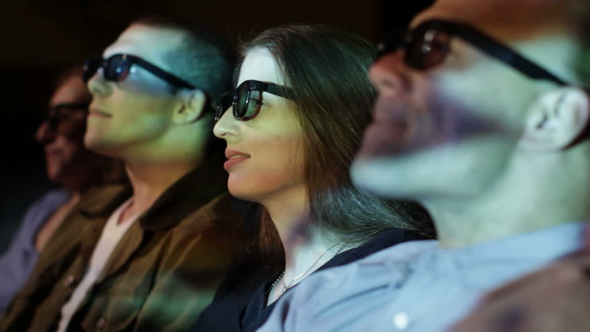 Young woman and friends react to dramatic action as she watches a 3D movie.