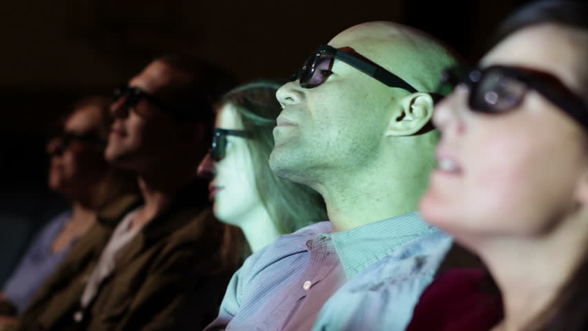 Young man watching a 3D movie with a group of friends. Focus on him with a small