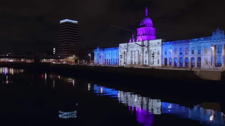 Establishing shot of Custom House and Liberty Hall reflecting on the River Liffey at night.