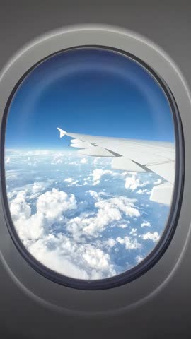 A View out of an airplane window onto a blue sky and clouds and sunlight