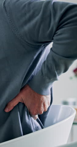 Home, senior man and massage with back pain for injury, muscle tension and osteoarthritis in retirement. House, male person and pensioner with discomfort for bone ache, fibromyalgia and inflammation