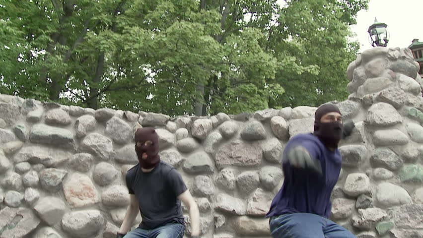 Two masked criminals jump over a wall on their way to or from a crime scene.