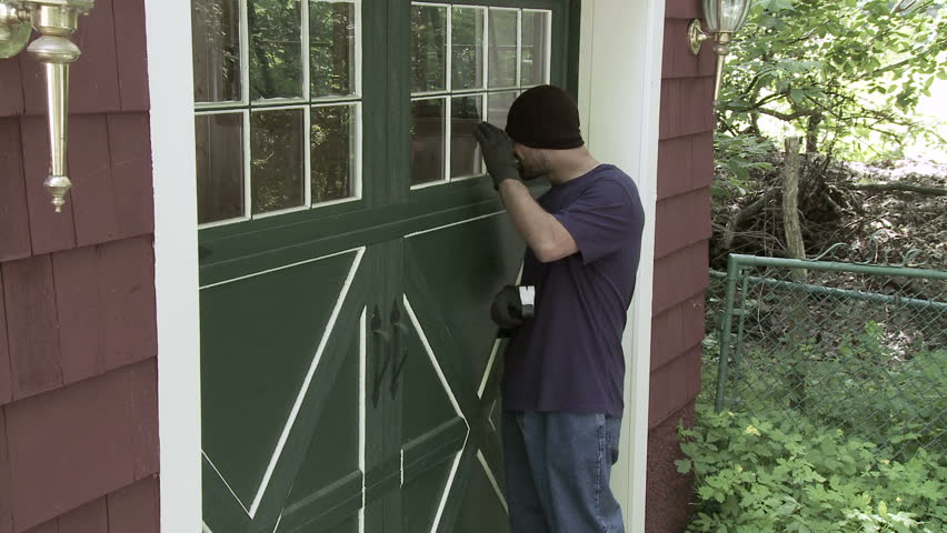 Burglar checks through garage window then goes around to door where he tries to