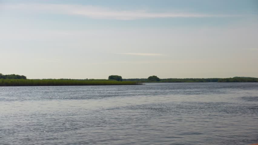 The Mississippi flows through green banks in fading Midwestern sunshine.