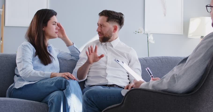 Psychologist helping a family couple address serious problems during a therapy session. Conversation providing support, consulting, and guidance to the couple improve relationship.