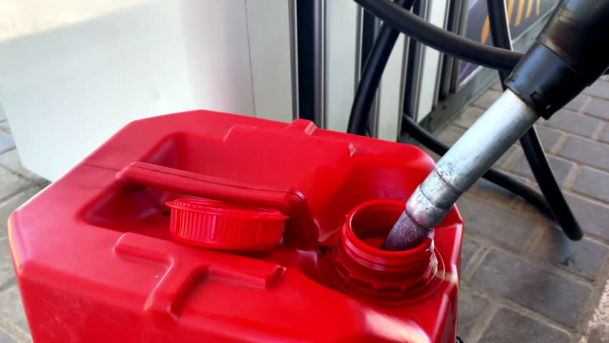 Driver refueling filling canister for car benzine gasoline fuel at gas station.Filling automobile's tank with gas fuel on trip,journey at station pump.fuel nozzle,petrol prices.Gasoline,petroleum.