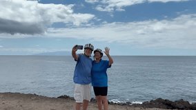 Happy senior couple of cyclists wearing helmets take a selfie with phone enjoying riding seaside with bicycles in a sunny day. Healthy lifestyle in retirement. Horizon over the sea - Powered by Shutterstock - Get 15% off with code: PIKWIZARD15