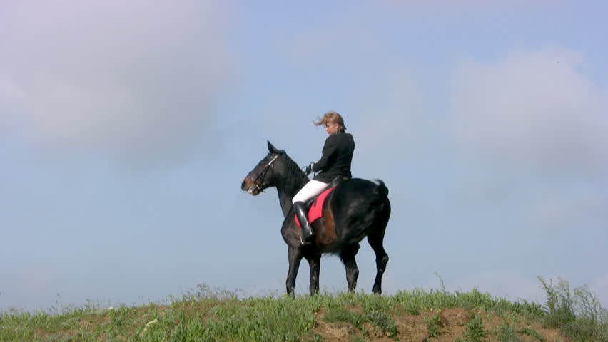 Thoroughbred horse black suit with a young horsewoman hoof beats against the