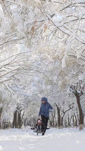 Happy family enjoy winter, cheerful father taking children sledding through a snowy park. Active father with kids playing outdoors. Winter fun, holiday, active lifestyle. Vertical shot