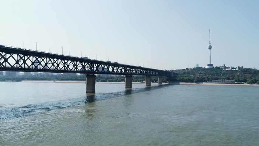 An aerial view of the Wuhan Yangtze River Bridge with a steady flow of cars traversing its length