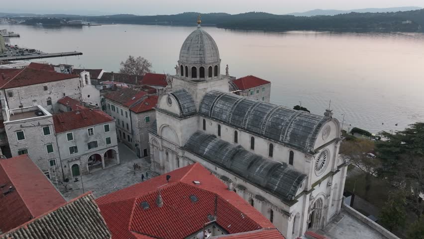 Aerial view of the Cathedral of St. James in Sibenik, Croatia, highlighting its iconic design, surrounded by historic buildings and a picturesque coastal setting in bright daylight.