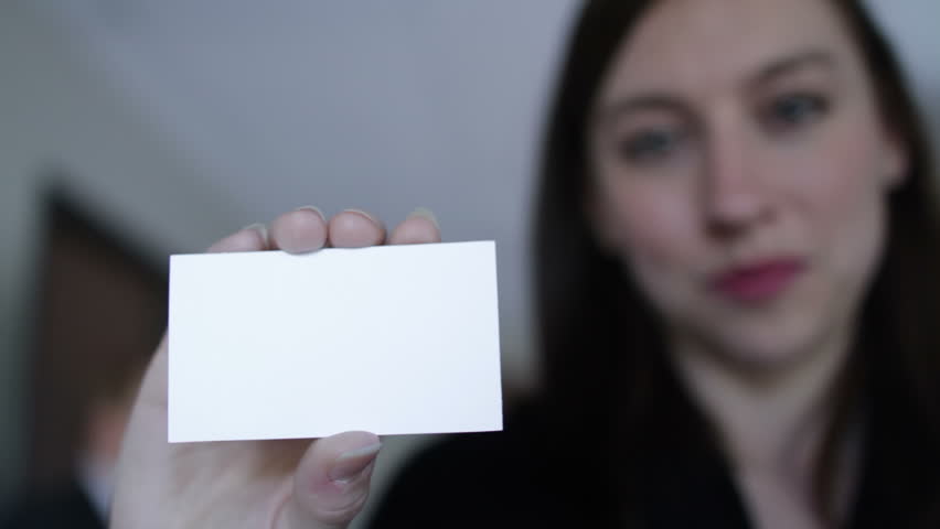 Young woman holds up a blank business card to the camera. If last frame is