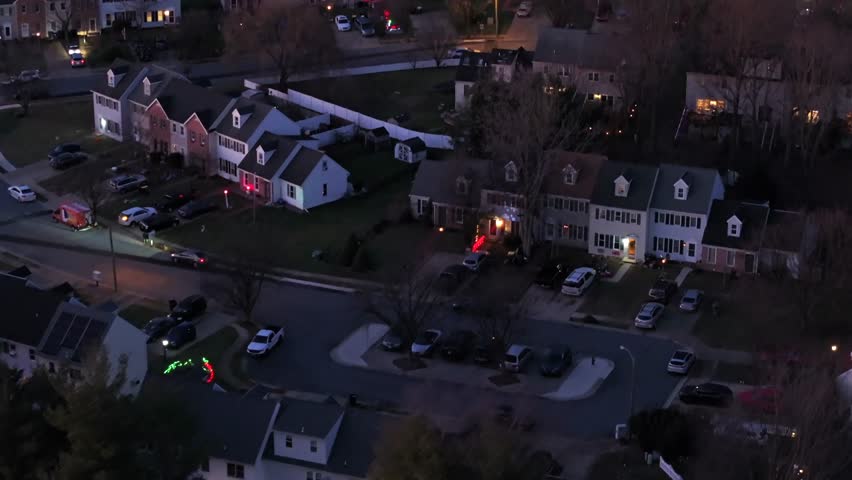 Aerial establishing shot of quiet american neighborhood during sunset time. Winter day in the evening. Top down flyover. Row of houses in new modern suburb district. Christmas decoration in garden.