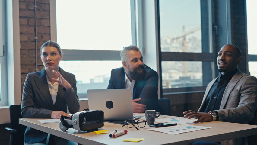 Diverse business team engaged in a professional meeting at a modern office, with VR headset and digital devices on the table. Concept of teamwork, innovation, and collaboration - Powered by Shutterstock - Get 15% off with code: PIKWIZARD15