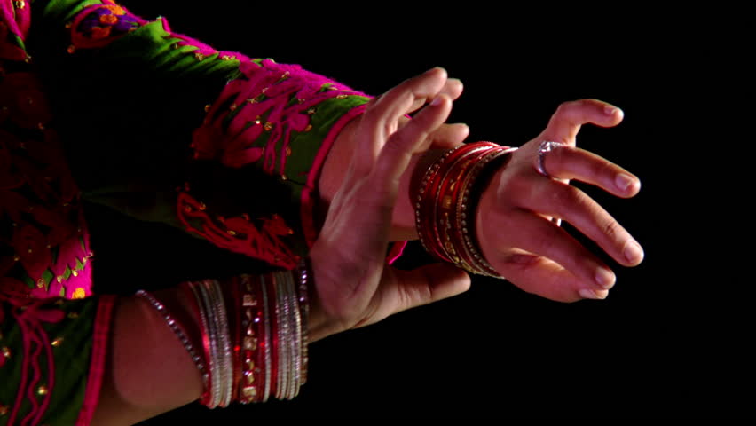 Indian girl in traditional dance costume checks through her wrist bangles. Close