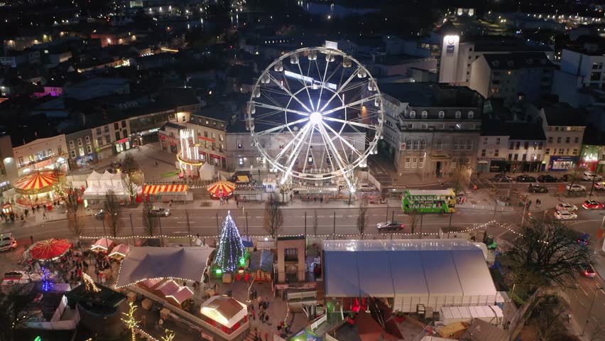 Galway , Ireland - 12 26 2024: Drone descends over Eyre Square festive Christmas Market with sparkling lights shining around vibrant city center at dusk