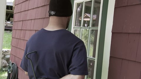 Burglar checks through garage window then goes around to door where he tries the handle and discovers the door is unlocked. Hand held shot.