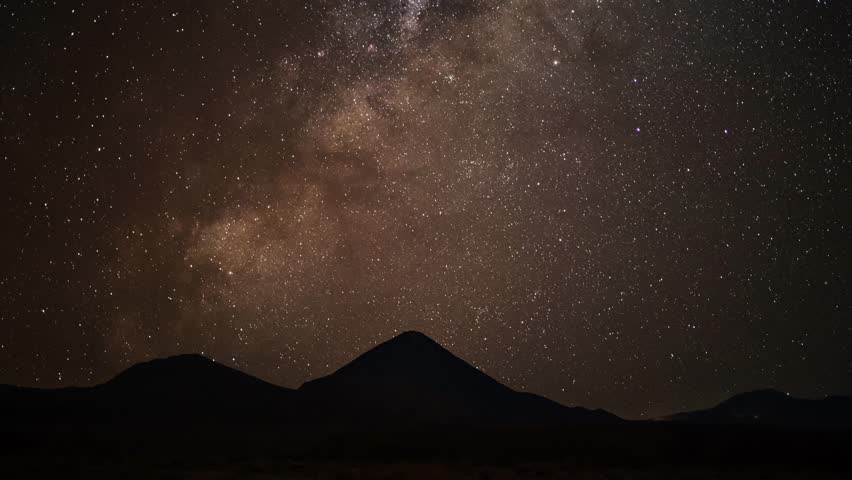 A stunning timelapse of glowing, starry night sky over the silhouetted mountain of Licancabur Volcano in Chile