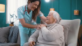 Friendly nurse smiling warmly talking with old 80s woman sitting in an armchair, providing compassionate care and helping elderly patients at home - Powered by Shutterstock - Get 15% off with code: PIKWIZARD15