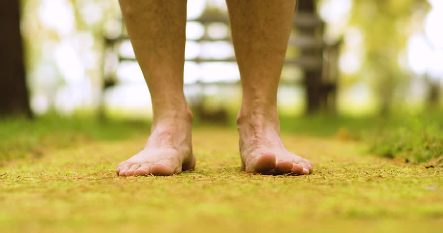Bare feet of a man on the ground. Yoga and unity with nature. Touching the ground to receive the power of the earth. Close-up 4k footage.