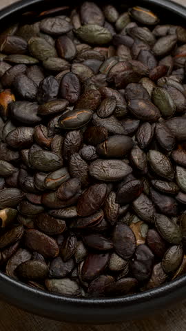 Toasted pumpkin seeds in a bowl. Table spin. Vertical video.