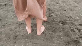 A woman enjoys the sandy beach and plays with the grains. A closeup of a white woman in a beige dress playing with her hand in the sand on a warm beach during the light breeze. - Powered by Shutterstock - Get 15% off with code: PIKWIZARD15