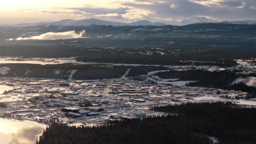Aerial view of Whitehorse, Yukon, during sunset. Snowy landscapes and the frozen Yukon River glow under the golden light of golden hour.
