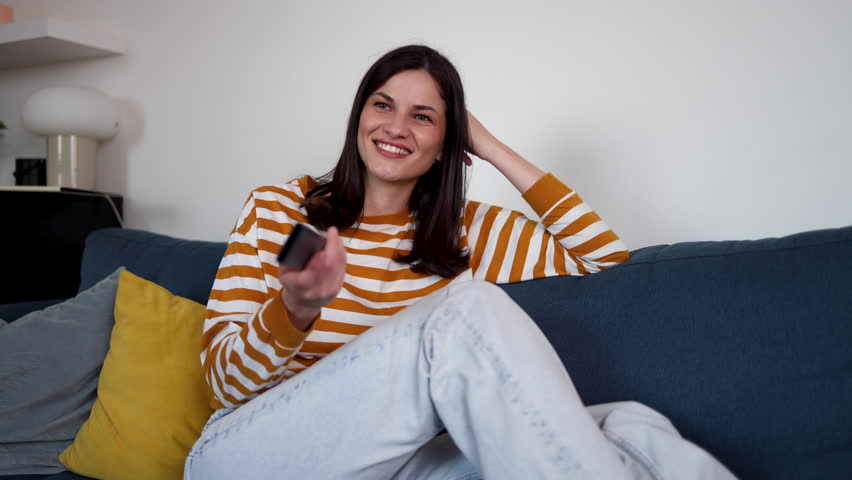 Young woman watching TV and having fun