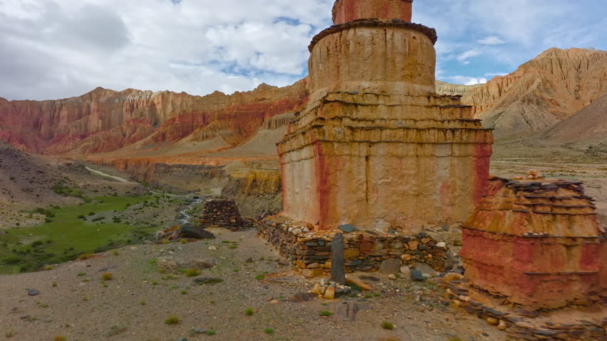 A serene view of a sacred Tibetan Chorten standing proudly amidst the rugged mountains of Upper Mustang, Nepal