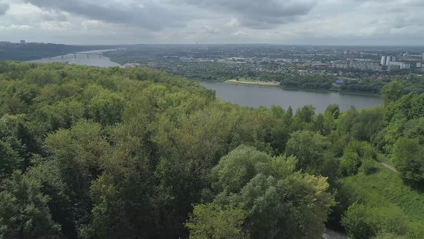 Beautiful view of a forest with a river in the background. The trees are lush and green, and the river is calm and peaceful. The city of Nizhny Novgorod, near the Oka River. Russia