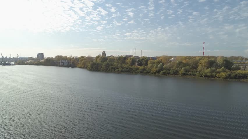 Calm body of water with a few trees in the background. The sky is clear and the sun is shining. The city of Nizhny Novgorod, near the Oka River. Russia