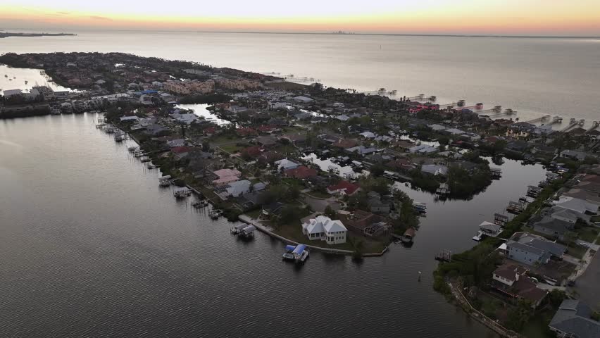 Aerial wide shot of Apollo Beach Island with private pier and luxury houses on island. Sunset time with bay in distance. Dusk scene with luxury neighborhood near Tampa City, Florida.