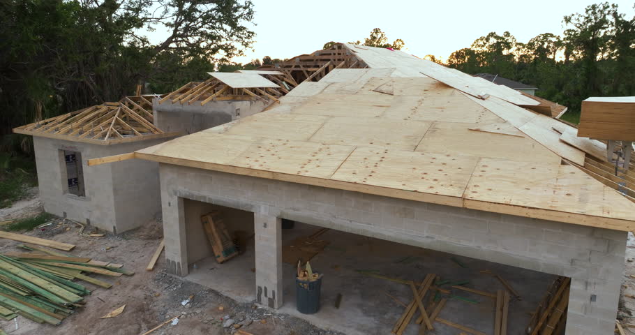 Roofing construction at new house building site. Unfinished plywood rooftop of residential home in Florida suburban area. Housing development concept