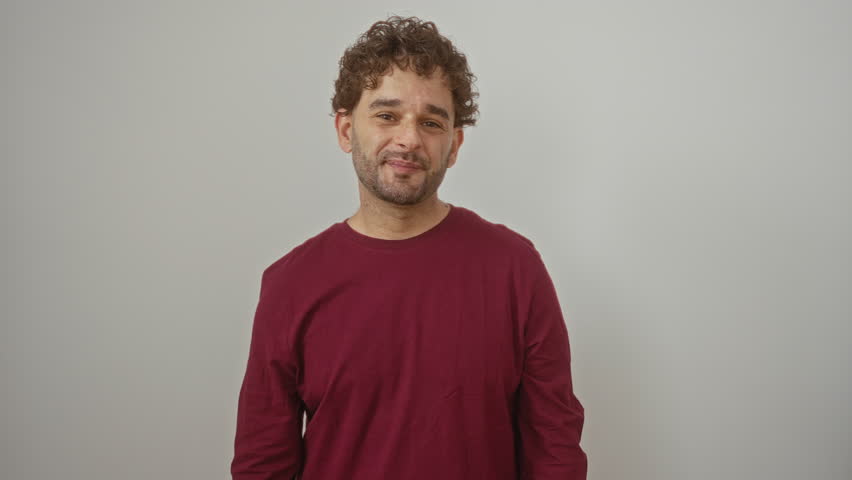 Young hispanic man standing and smiling while wearing t shirt, pointing finger to head signifying great idea and good memory over isolated white background