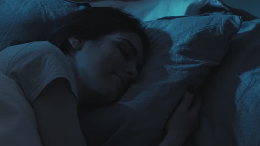 Night rest. Peaceful sleep. Relaxed calm happy woman enjoying dreaming on soft comfortable soft pillow in bed in dark home bedroom.