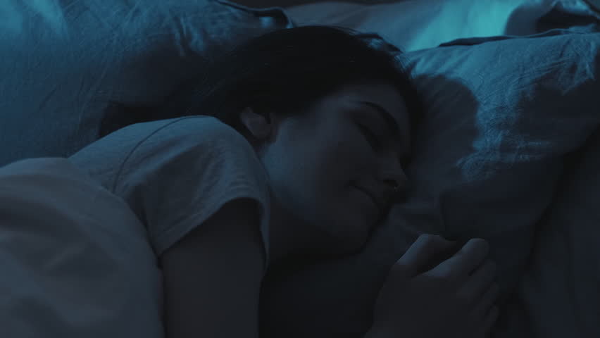 Night rest. Peaceful sleep. Relaxed calm happy woman enjoying dreaming on soft comfortable soft pillow in bed in dark home bedroom.