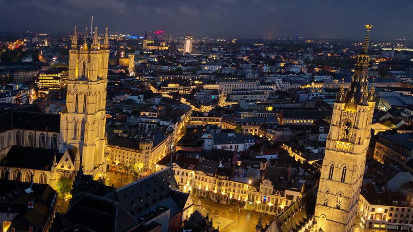 Aerial hyperlapse at night above Ghent old town, a beautiful city in Belgium, with the famous Tower Row of St. Nicholas Church, Belfry and St. Bavo