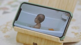 Parents using ip wireless security camera as baby video monitor on mobile phone. Parent watching little child bathing in bathtub on smartphone screen in real-time. - Powered by Shutterstock - Get 15% off with code: PIKWIZARD15