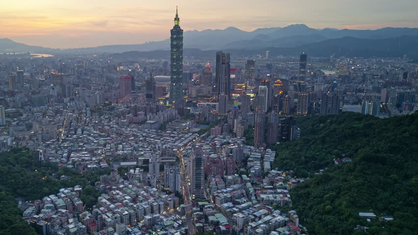 Aerial hyperlapse at sunset above Downtown Taipei, the vibrant capital of Taiwan, with 101 Tower standing out amid skyscrapers in XinYi Commercial District and city lights dazzling under twilight sky