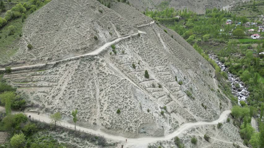 A dramatic aerial shot of dangerous, winding roads cutting through rugged, rocky terrain, highlighting the thrill of navigating such challenging landscapes.