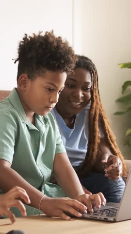 Mother and son celebrating success using laptop. Vertical