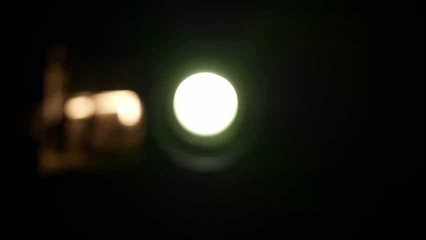 Smoke and dust moving the backlight from the lens of an old 1970s slide projector.The lens of an old projector